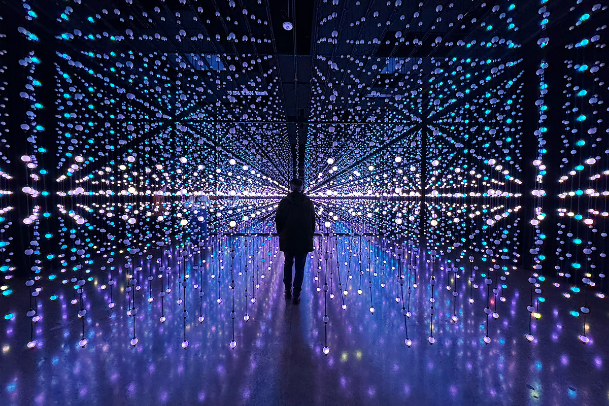 man walking through blinking light strands at an art museum one of the best things to do in Portland Oregon during winter