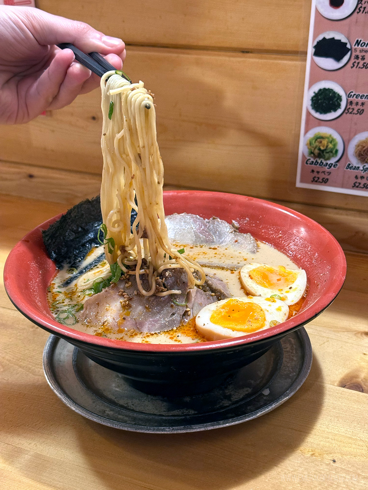 person pulling noodles out of a bowl of ramen enjoyed on their Big Island Hawaii itinerary