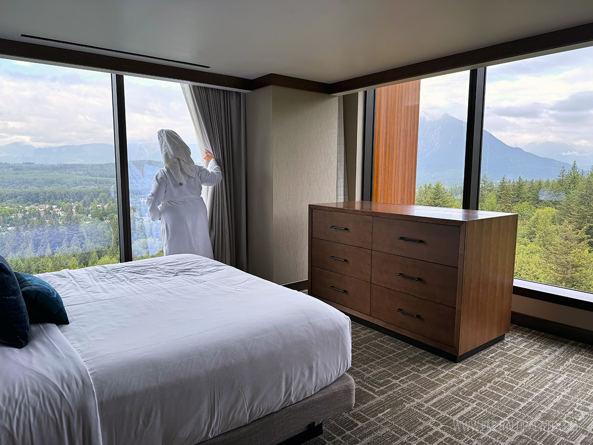 woman in robe and towel on head looking out window at mountain views from Snoqualmie Casino & Hotel room